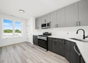 Thumbnail 5 of 27 - A modern kitchen with a white countertop and dark wood cabinets.