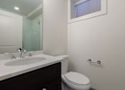 Thumbnail 6 of 13 - A white toilet sits next to a sink in a bathroom.