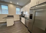 Thumbnail 5 of 20 - A kitchen with a refrigerator, oven, and microwave.