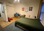 Thumbnail 18 of 25 - A bedroom with a bed, desk, chair, and a ceiling fan.