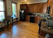 Thumbnail 5 of 13 - A kitchen with wooden cabinets and a black fridge.