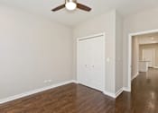 Thumbnail 6 of 17 - A room with a ceiling fan and wood flooring.