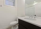 Thumbnail 5 of 13 - A white toilet sits next to a white sink in a bathroom.