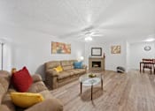 Thumbnail 6 of 37 - A living room with a brown couch and a glass coffee table.