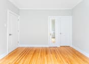 Thumbnail 22 of 24 - A room with wooden floors and white walls with two doors.