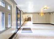 Thumbnail 4 of 24 - A hallway with a staircase in the background and a light on the ceiling.