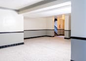 Thumbnail 5 of 24 - A hallway with a staircase in the background.