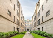 Thumbnail 1 of 24 - A long, narrow courtyard between two buildings with greenery on the sides.