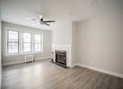 Thumbnail 14 of 24 - A spacious living room with a fireplace and a ceiling fan.