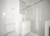 Thumbnail 12 of 24 - A white bathroom with a sink, toilet, and shower.