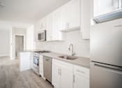 Thumbnail 7 of 24 - A kitchen with white cabinets and appliances.