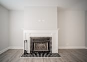Thumbnail 17 of 24 - A fireplace with a black grate in a room with white walls.