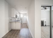 Thumbnail 11 of 24 - A modern kitchen with white cabinets and a wooden floor.