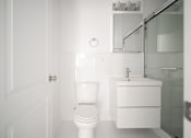 Thumbnail 13 of 24 - A white toilet sits next to a sink in a bathroom.