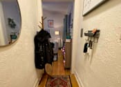 Thumbnail 16 of 25 - A hallway with a rug on the floor and a coat hanging on the wall.
