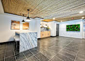 Thumbnail 7 of 9 - A kitchen with a marble island and a wooden ceiling.