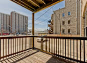 Thumbnail 14 of 17 - A wooden deck with a railing and a view of a cityscape.