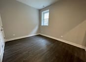 Thumbnail 8 of 20 - A room with wooden flooring and a small window.