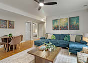 Thumbnail 23 of 31 - A living room with a blue couch and a ceiling fan.