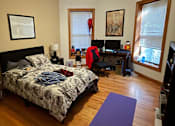 Thumbnail 8 of 13 - A bedroom with a bed, desk, and chair.