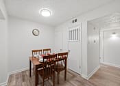Thumbnail 9 of 37 - A dining room with a wooden table and chairs.