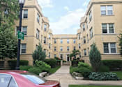 Thumbnail 1 of 17 - A red car is parked on the side of a street in front of a building with a green bike sign.