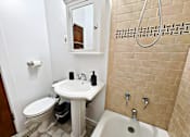 Thumbnail 5 of 17 - A bathroom with a toilet, sink, and bathtub.