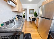 Thumbnail 3 of 17 - A modern kitchen with a stainless steel refrigerator and a dining area with a table and chairs.
