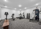 Thumbnail 32 of 60 - A gym with a bench, weights, and exercise equipment.
