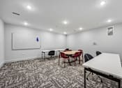 Thumbnail 34 of 60 - A room with a white table and chairs, a whiteboard, and a blue object on the whiteboard.