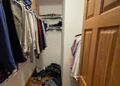Thumbnail 9 of 13 - A hallway with a wooden door and clothes hanging on a rack.