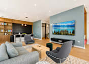Thumbnail 2 of 18 - A living room with a grey couch, a chair, and a television.