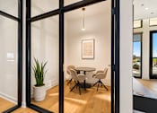 Thumbnail 11 of 18 - A room with a table and chairs is visible through a glass door.