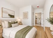 Thumbnail 15 of 18 - A bedroom with a bed, nightstand, and a painting on the wall.