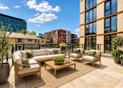 Thumbnail 17 of 18 - A patio with a couch, chairs, and a coffee table.