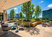 Thumbnail 6 of 18 - A patio with chairs and a table with a view of the city.