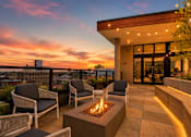 Thumbnail 7 of 18 - A patio with a fire pit and chairs is set against a sunset sky.