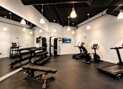 Thumbnail 9 of 18 - A gym with a variety of equipment including treadmills, weights, and exercise machines.