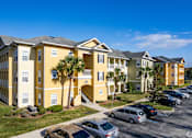 Thumbnail 2 of 37 - A yellow building with a parking lot in front.