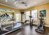 Thumbnail 12 of 37 - A spacious home gym with treadmills, elliptical machines, and a fan.