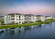 Thumbnail 26 of 37 - A large apartment complex sits next to a body of water.