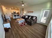 Thumbnail 19 of 35 - A living room with a brown couch and a wooden floor.