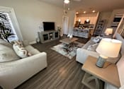 Thumbnail 17 of 35 - A living room with a grey couch, a coffee table, and a television.