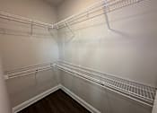 Thumbnail 31 of 35 - Empty walk-in closet with white shelving and wooden floors.