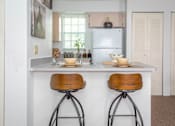 Thumbnail 8 of 24 - A kitchen with a white countertop and two bar stools.