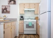 Thumbnail 6 of 24 - A kitchen with a white fridge, white stove, and wooden cabinets.