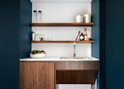 Thumbnail 30 of 31 - A modern kitchen with a wooden counter and shelves.
