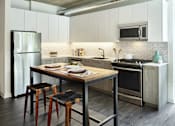 Thumbnail 14 of 31 - A modern kitchen with a wooden table and bar stools.
