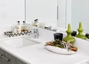 Thumbnail 18 of 31 - A bathroom with a white sink and two framed black and white pictures on the wall.