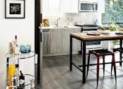 Thumbnail 17 of 31 - A kitchen with a black fridge, a wooden table and a bar cart.